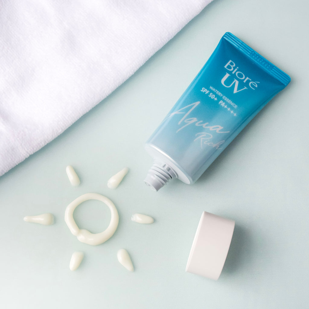 Biore UV Aqua Rich Watery Essence SPF50+/PA++++ in a tube with cream drops and a sun design on a light background.